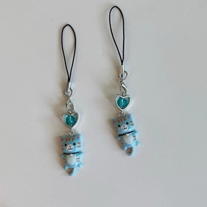Close-up of blue Y2K cat phone charms with heart beads and silver metal hardware