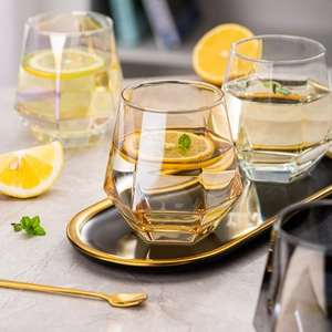 Detail of three hexagonal whiskey glasses in clear, amber, and iridescent finishes on a tray