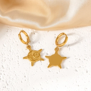 Detail of gold sun and star charm earrings on silk fabric background with professional lighting