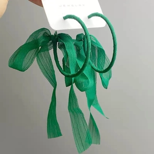 Macro detail of emerald green hoop earrings with silk ribbon on jewelry card