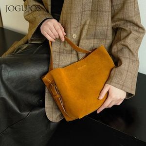 Detail of yellow suede bucket bag featuring adjustable strap and brand logo