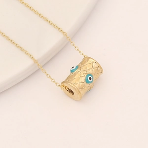 Macro detail of gold evil eye pendant with diamond texture on a delicate chain