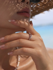 Detail of a stainless steel double-row ring with pearls and pink gems on a finger