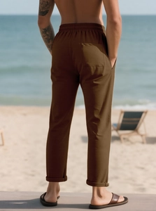 Vista posteriore dei pantaloni casual da uomo marroni con elastico in vita sulla spiaggia