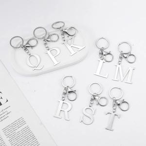 Polished stainless steel alphabet keychains with lobster clasps and rings on a white tray