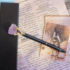 Détail d'un stylo à bille en métal créatif avec cristal brut violet sur papier vintage
