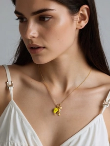 Close-up of gold stainless steel necklace with grape, shell, and star pendants on model