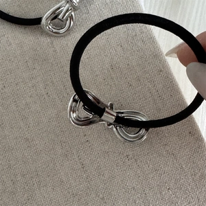 Detailed macro view of a silver metal 3D bow on a black high-elastic hair tie