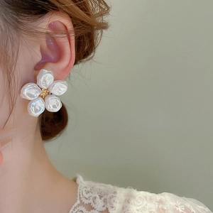 Dettaglio di eleganti orecchini a fiore con perle barocche indossati da una modella