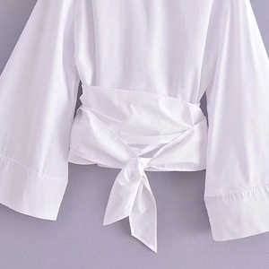 Blouse portefeuille blanche élégante avec manches évasées et lien à la taille