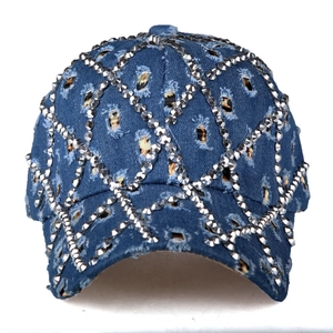 Dettaglio macro del cappello in denim con strass argentati brillanti e motivo a griglia