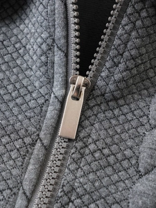 Macro detail of the silver metal zipper and grey argyle knit texture on the sweatshirt