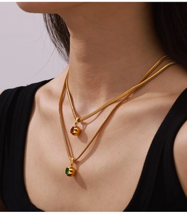 Close-up of double layer gold snake chains with ball pendants and colorful zircon stones
