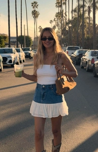 Outdoor street style shot of a denim and white lace patchwork mini skirt at sunset