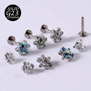 Macro view of G23 titanium labret studs with opal and cubic zirconia flower designs