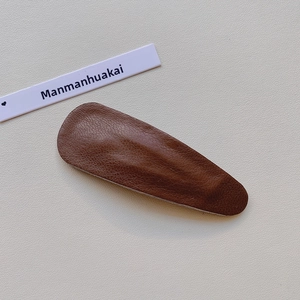 Macro detail of dark brown faux leather hair clip with a vintage lychee texture