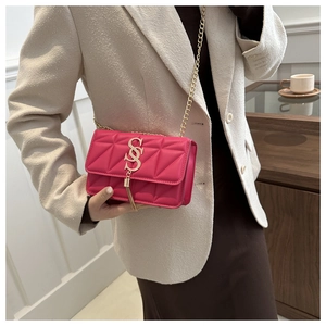 Detail of fuchsia quilted crossbody bag featuring gold S logo and chain strap
