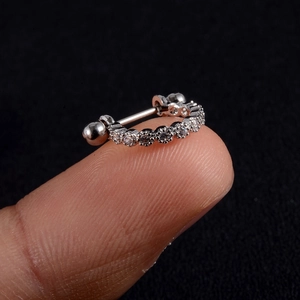 Macro shot of silver stainless steel cartilage stud with cubic zirconia held on a finger