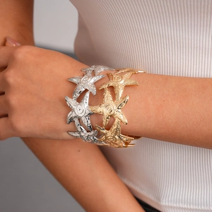 Detailed close-up of a wide starfish cuff bracelet with hammered metal texture in gold color