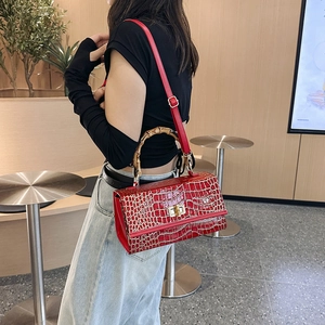 Red crocodile pattern leather bag featuring a distinctive bamboo handle and metal twist lock