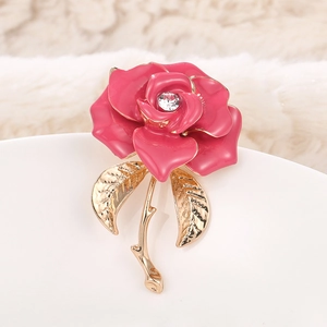 Macro detail of elegant pink enamel rose brooch with gold stem and sparkling rhinestone
