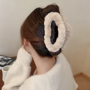 Detail of plush cream faux fur hair claw clip styled on a woman's hair in a cozy bun