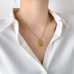 Vintage gold rectangular sunburst pendant necklace on a model with white shirt