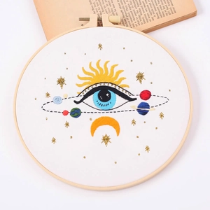 DIY embroidery kit with eye and celestial sun pattern in a wooden embroidery hoop