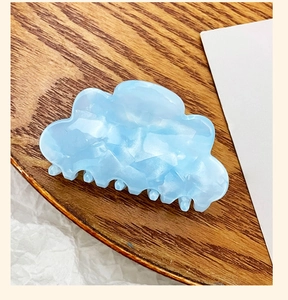 Cloud-shaped light blue acrylic hair claw with marble texture on wooden tray