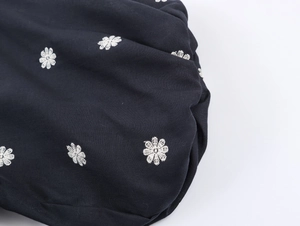 Close-up of white floral embroidery on deep blue short sleeve dress with bubble sleeves