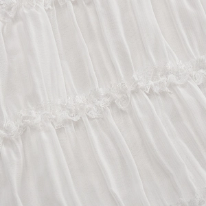 Macro detail of the white ruched fabric texture and delicate lace trim on the dress