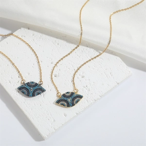 Detail of evil eye pendant necklace with blue cubic zirconia on white stone background