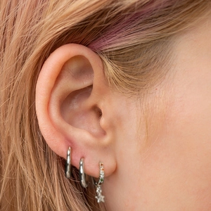 Close-up of S925 sterling silver asymmetrical star and moon hoop earrings on ear