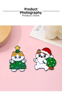Close-up of cute Christmas cat enamel pins in tree and Santa outfits on pink surface