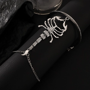 Close-up of silver scorpion finger bracelet with white rhinestones on dark leather