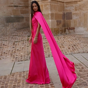 Elegant hot pink one-shoulder bodycon maxi dress with long flowing sash detail on stone street