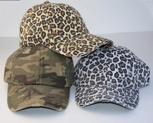 Detail of distressed leopard print baseball caps with vintage frayed edges and camo patterns