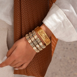 Vintage hollow-out geometric gold bangle and multi-layer bracelet on woman's wrist