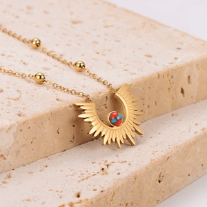 Golden stainless steel sunburst pendant necklace with colorful beads on stone surface