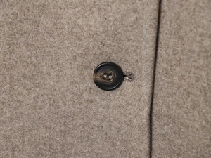 Gros plan sur la texture laineuse et le bouton noir d'une veste décontractée pour femme