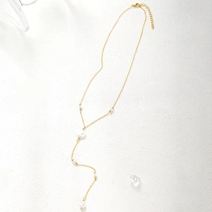 Macro detail of gold-plated pearl tassel necklace with adjustable lobster clasp closure