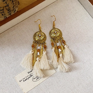 Detailed macro view of bohemian tassel earrings with crystal studs and golden feathers