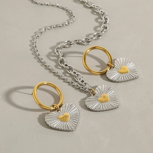 Detail of mixed-metal heart pendant set with sunburst texture on necklace and earrings