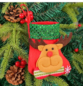 Details eines roten Nikolausstiefels mit grünen Pailletten und Rentier-Puppe am Baum