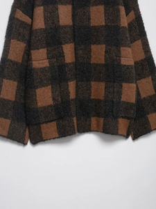 Macro detail of brown and black checkered knit cardigan featuring soft plush texture and pockets