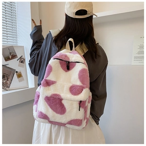 Detail showing plush pink and white cow print texture on a fuzzy winter backpack
