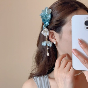 Détail d'une pince à cheveux en fleur de soie avec glands perlés portés de profil