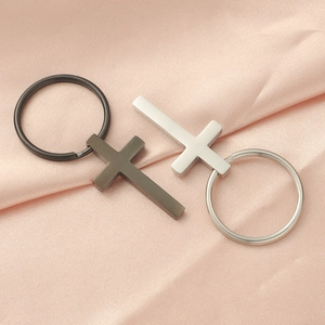 Macro detail of gunmetal and steel cross pendants on a smooth pink satin background