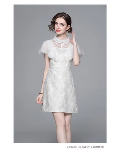 Détail d'une robe blanche à manches courtes avec volants en dentelle et jacquard doré