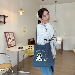 Detail of striped canvas bag with cute puppy embroidery and Puppyland text in a cafe